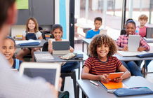 Salle de classe avec des élèves et un enseignant. Tous les élèves ont une tablette en main.